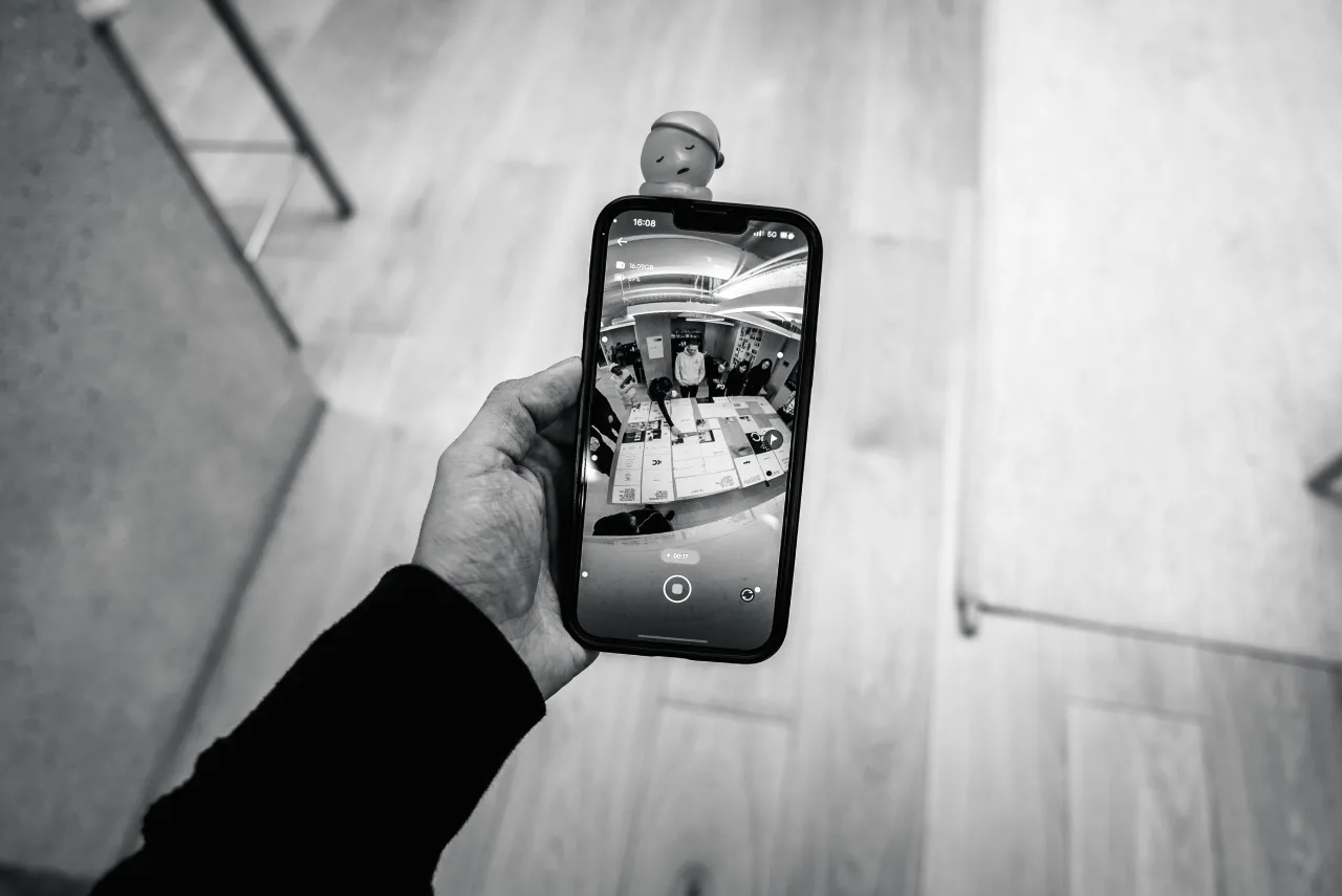 Hand holding a smartphone displaying the interior of a modern building with curved architecture in black and white